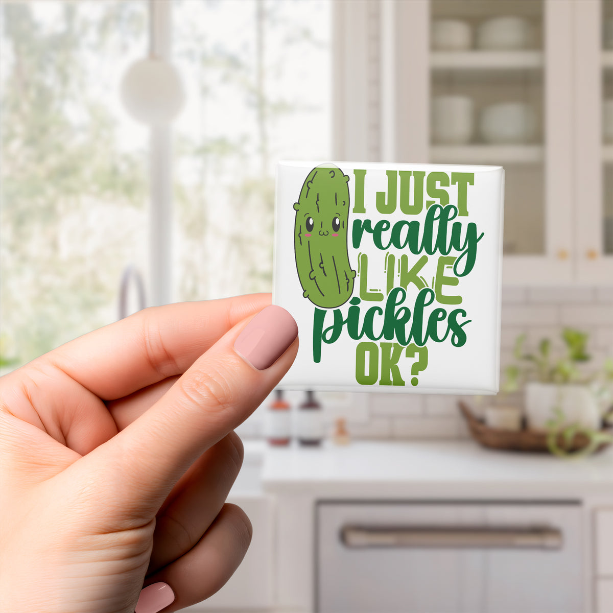 A person's hand holding a sticker with a cartoon image of a pickle and text that says "I JUST REALLY LIKE PICKLES OK?".