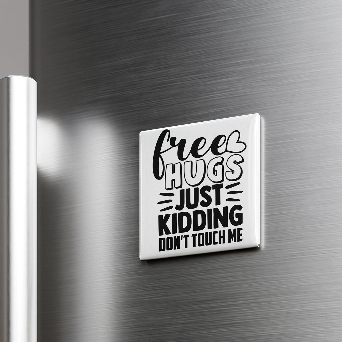 A white refrigerator door with a black and white magnet that says "Free Hugs Just Kidding Don't Touch Me".