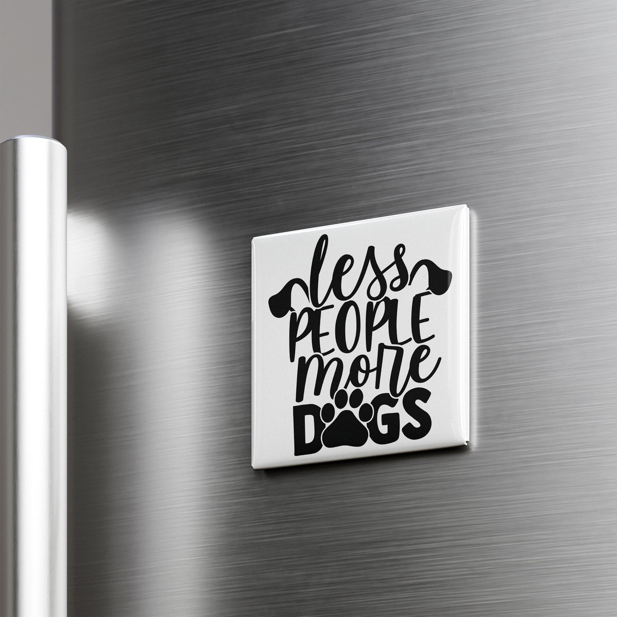 A white magnet with the text "less people, more dogs" printed on it is attached to a metallic surface.