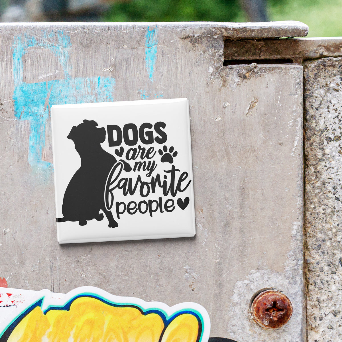 A sticker with the text "Dogs are my favorite people" is attached to a concrete surface.