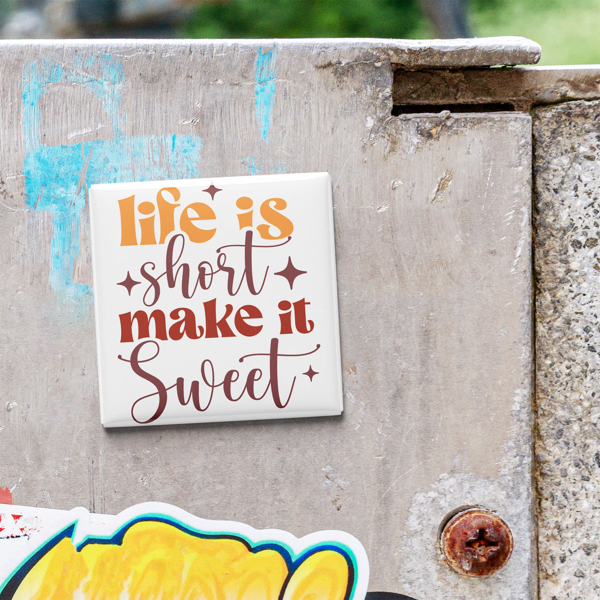 a sticker with the text "Life is short, make it sweet" on a concrete surface.