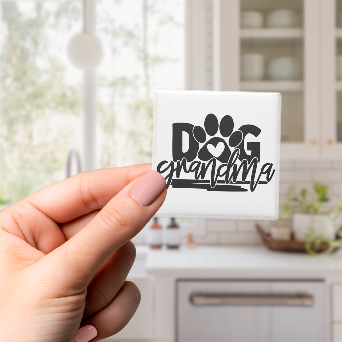 A hand holding a tile with the text "DOG grandmother" on it.