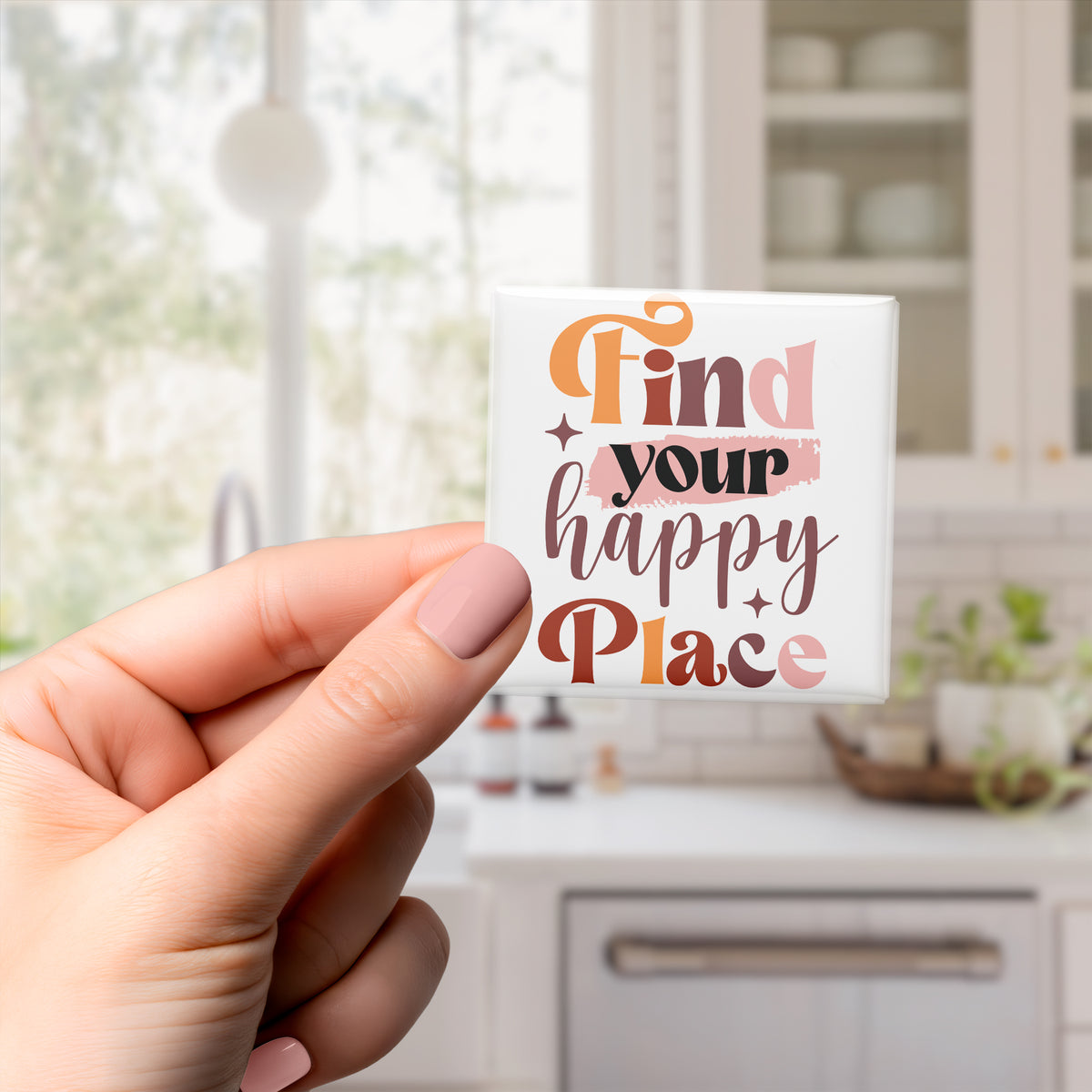 A hand holding a small white magnet with the text "Find your happy place" written on it.