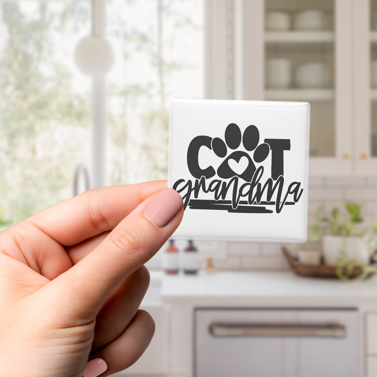 A hand holding a small square tile with the text "COT grandmother" on it.