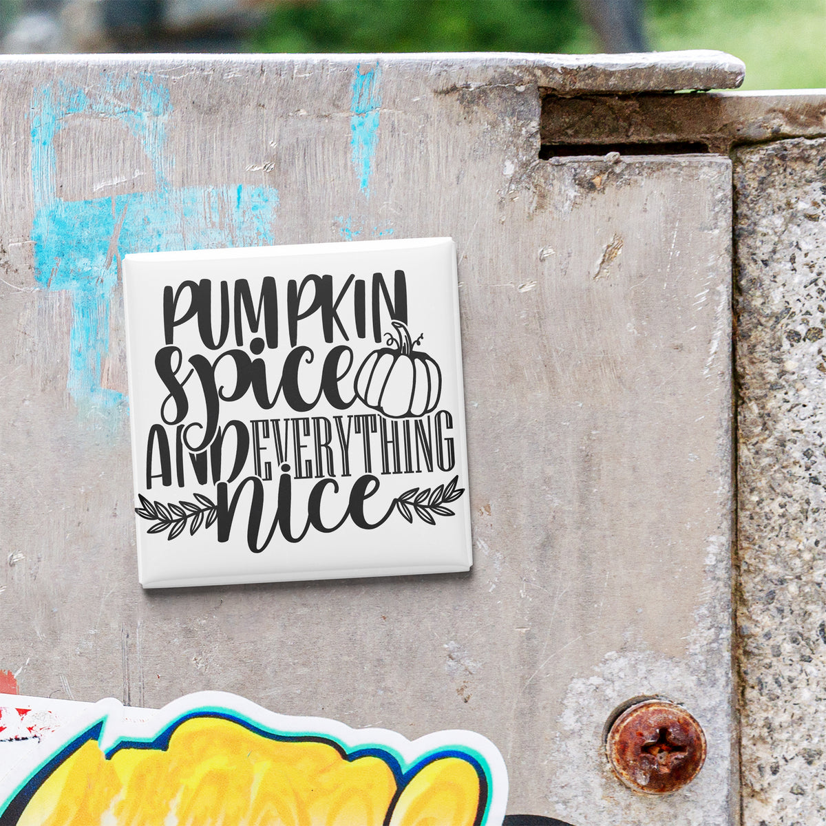 A white tile with black text that says "Pumpkin spice and everything nice" is attached to a concrete wall.