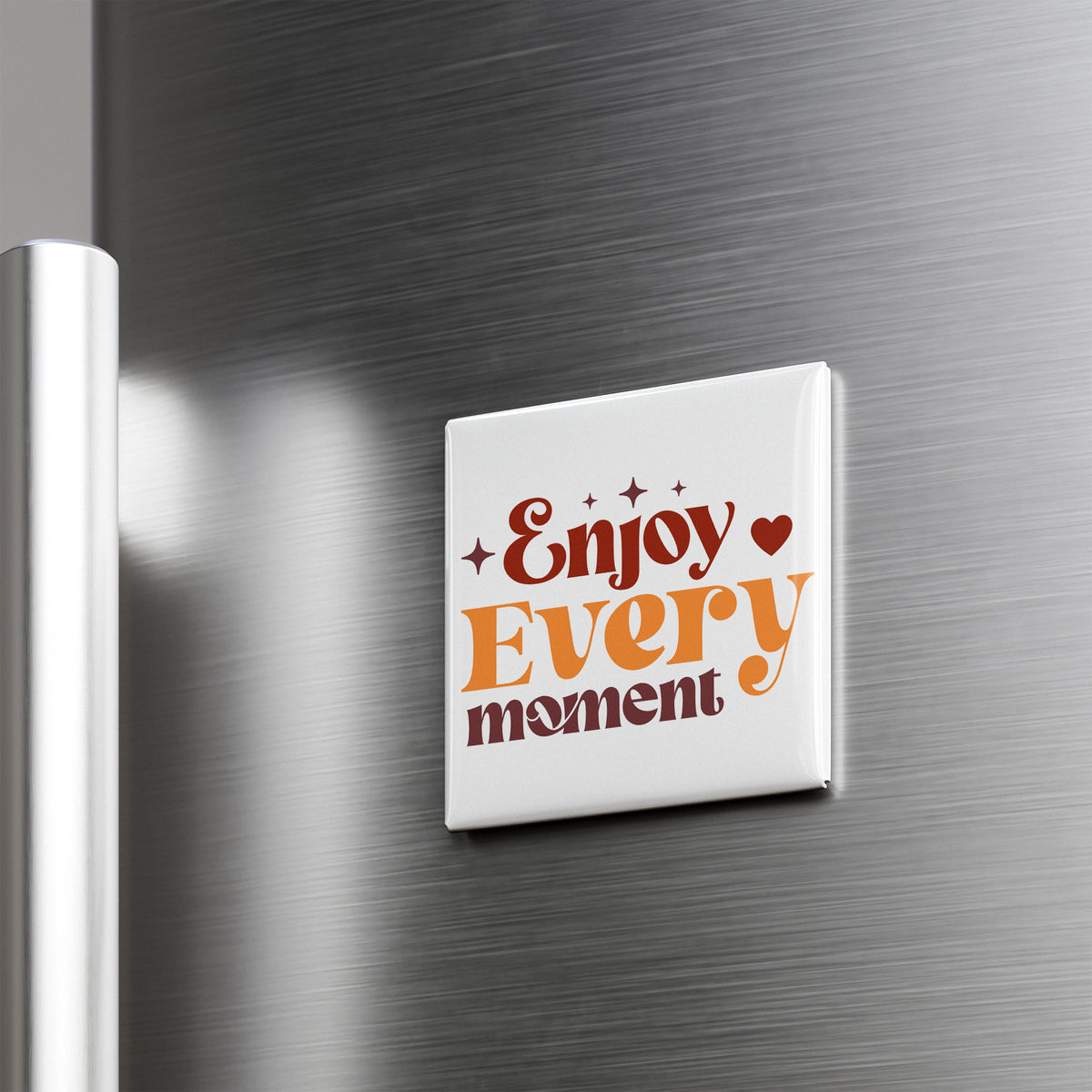 A white square magnet with the text "Enjoy Every moment" on it is attached to a metallic surface.