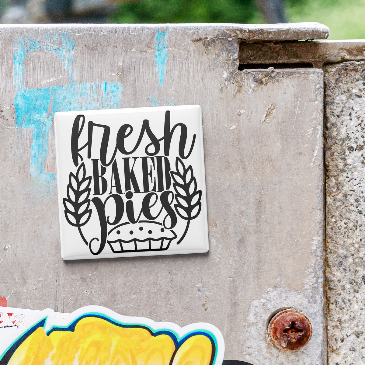 A white tile with the text "fresh baked pies" is attached to a concrete wall.