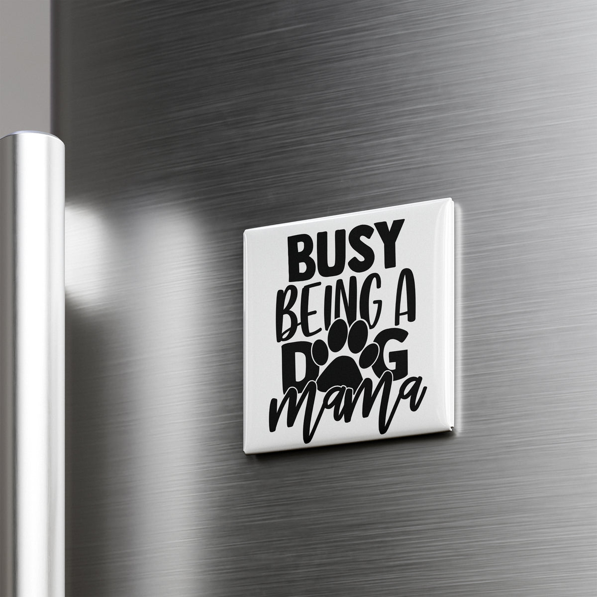 A white refrigerator magnet with the text "BUSY BEING A DOG MAMA" printed on it.