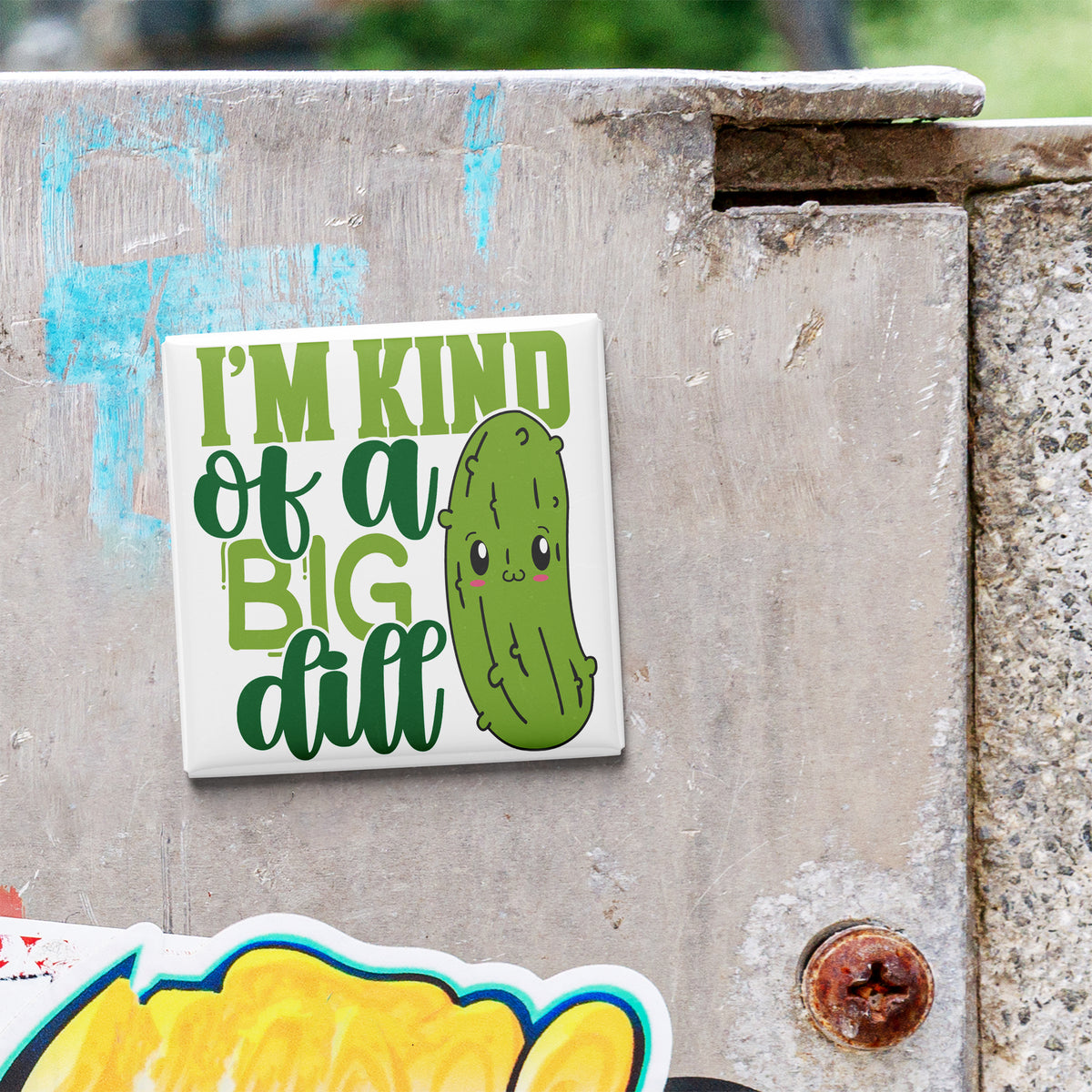 A sticker with a cartoon pickle and the text "I'm kind of a big dill" is attached to a concrete wall.