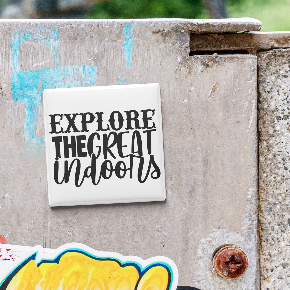 a sticker with the text "EXPLORE THE GREAT Indoors" on a concrete surface.