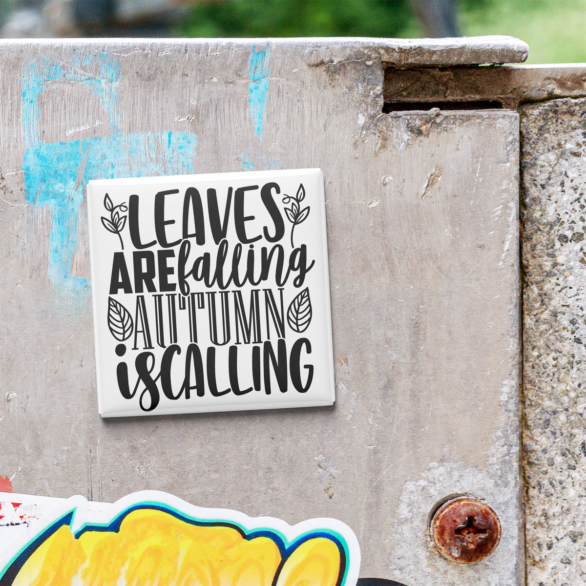 A sticker with the text "LEAVES ARE FALLING AUTUMN IS CALLING" is attached to a concrete surface.