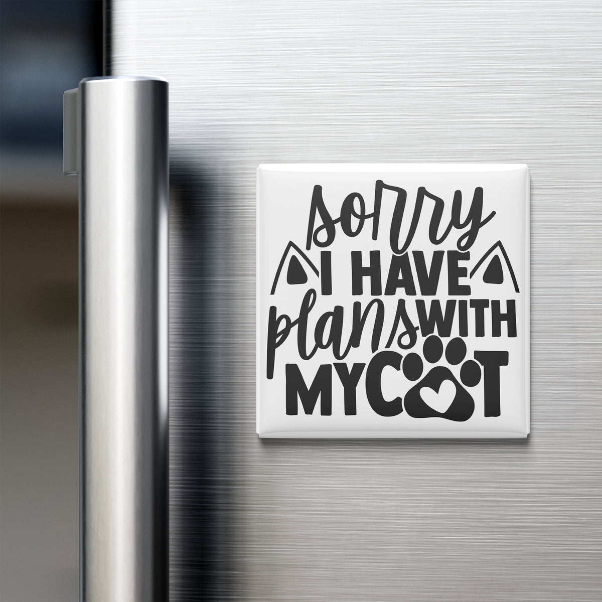 A refrigerator door with a magnet that says "Sorry I Have Plans With My Cat" in a stylized font.