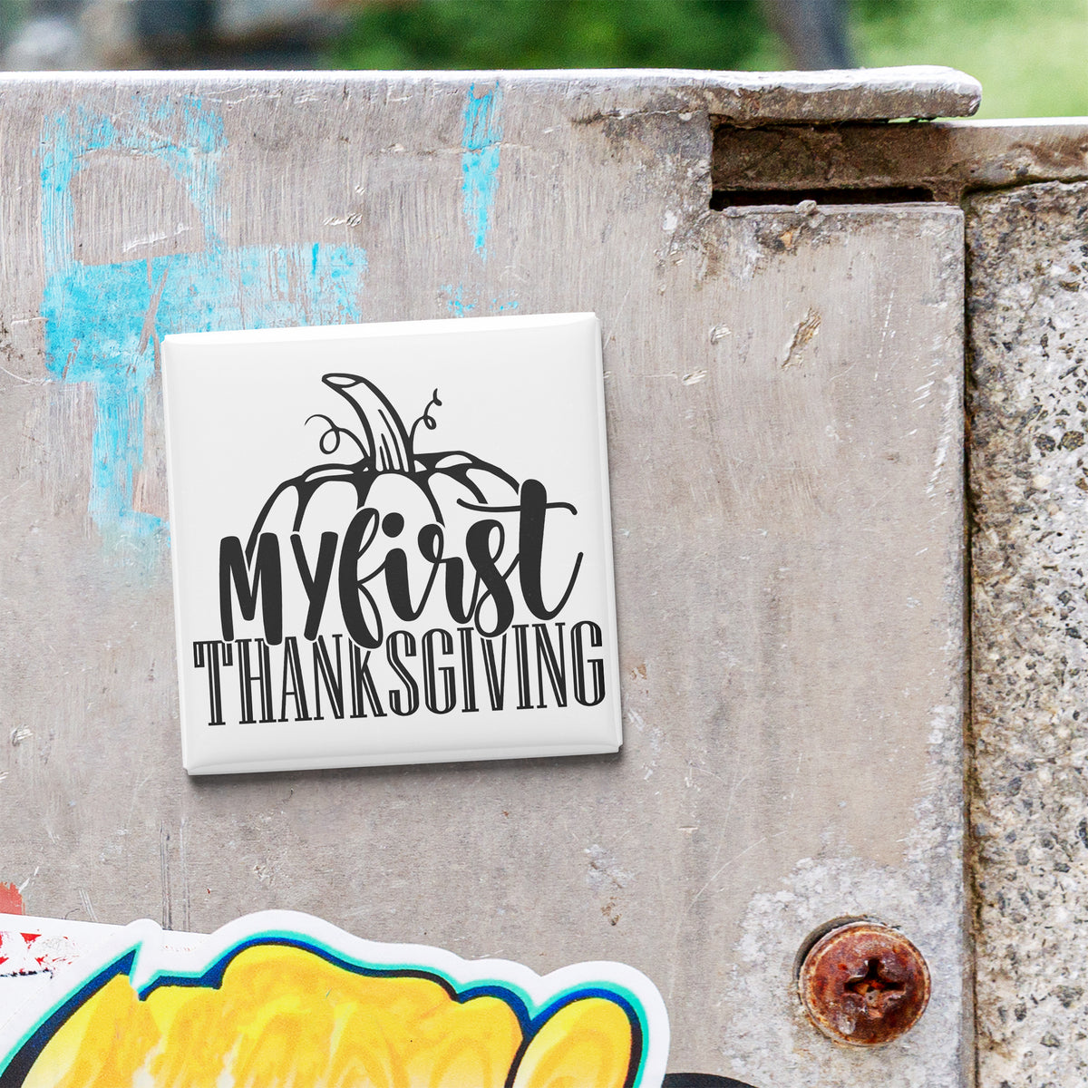 A white tile with the text "My first Thanksgiving" is attached to a concrete wall.