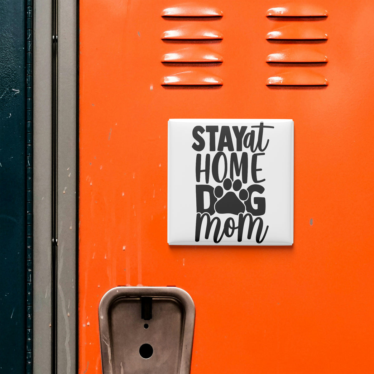 a sticker with the text "STAY AT HOME DOG MOM" on an orange surface, which appears to be a locker or a door.