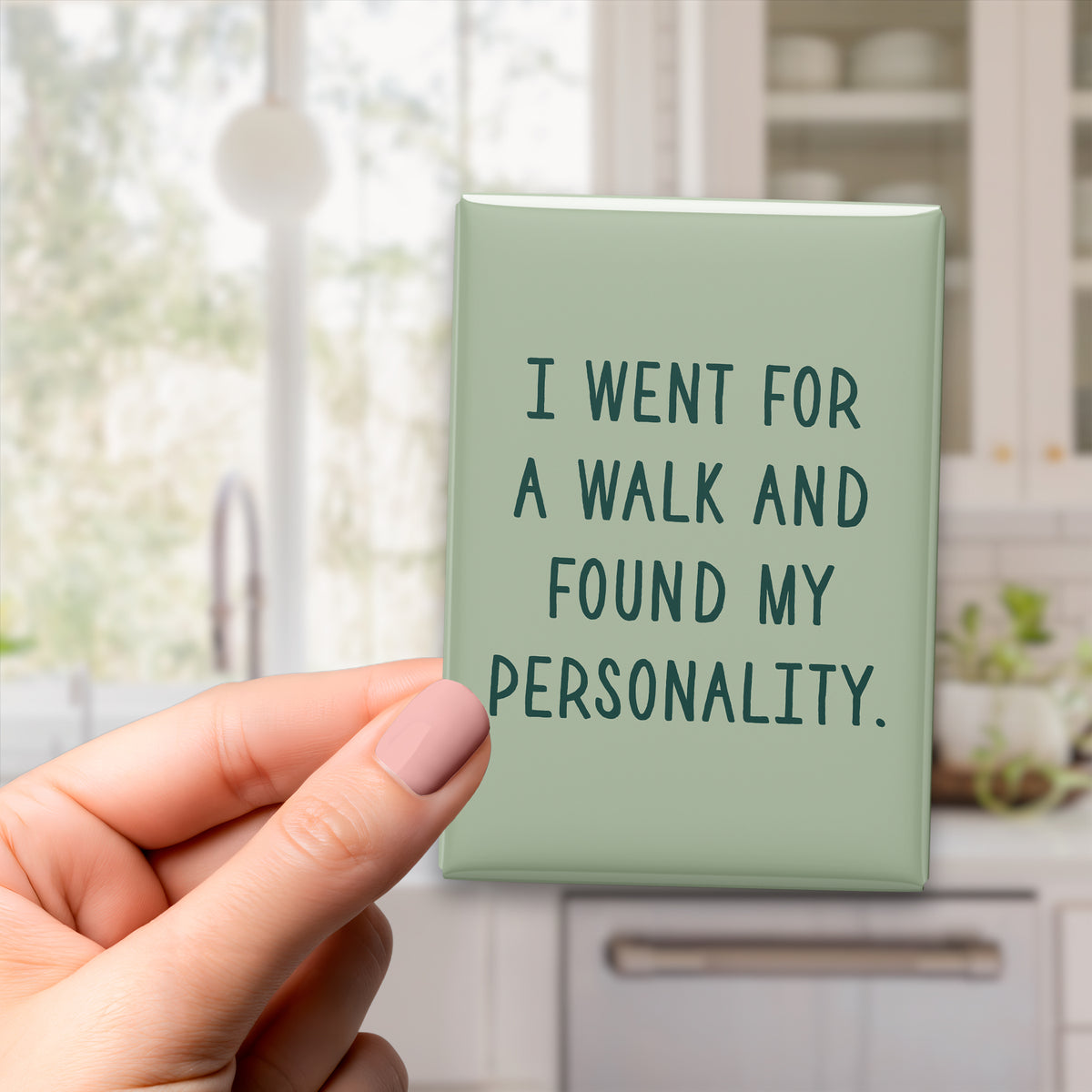 Hand holding the 2.5 × 3.5-inch “I went for a walk and found my personality.” magnet in a kitchen