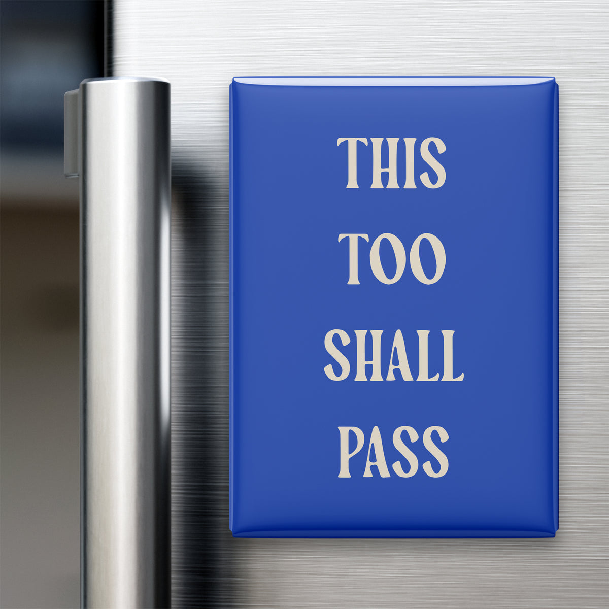 This Too Shall Pass magnet in Parchment lettering on a Cobalt background, displayed on a refrigerator