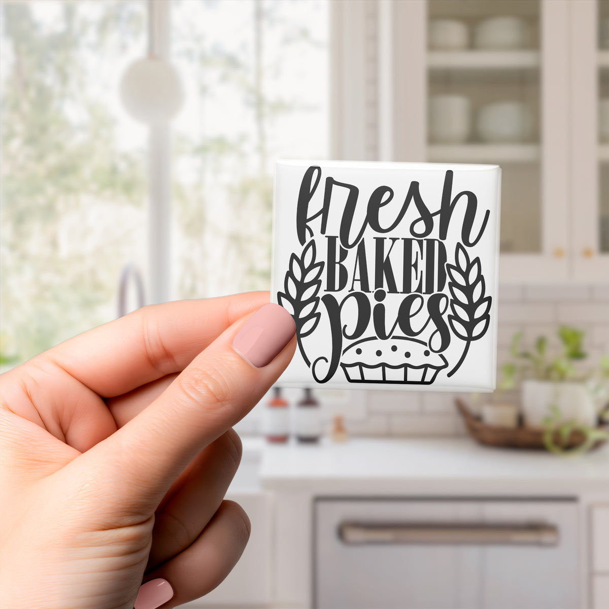 A hand holding a small white sticker with the text "Fresh Baked Pies" written on it.