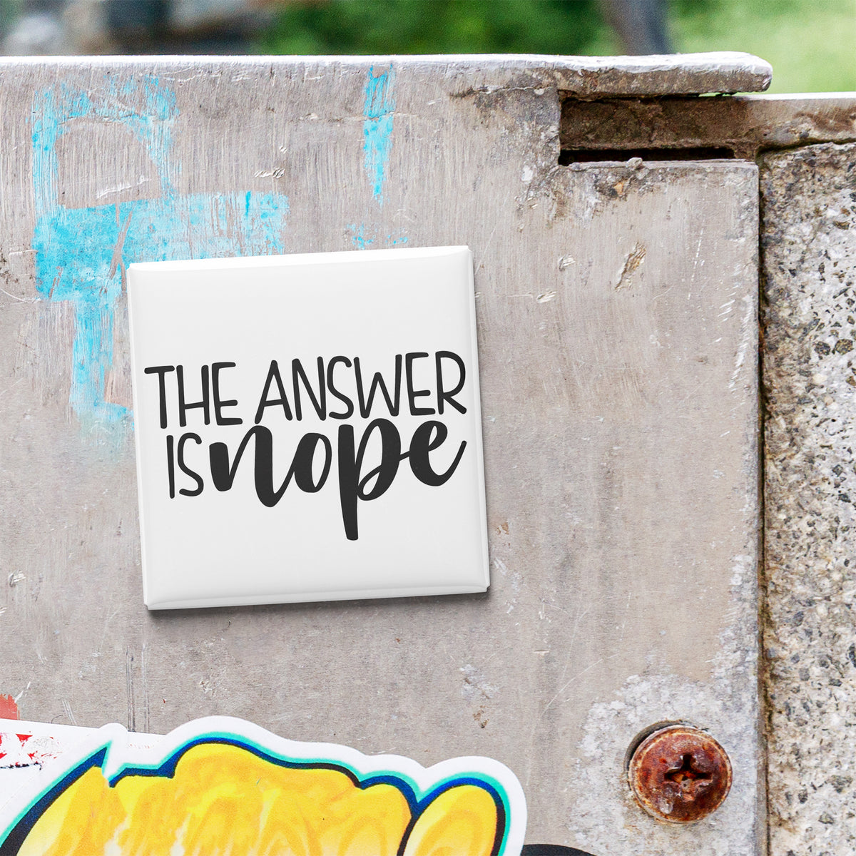 A white square magnet with the text "THE ANSWER IS NOPE" attached to a metal surface.