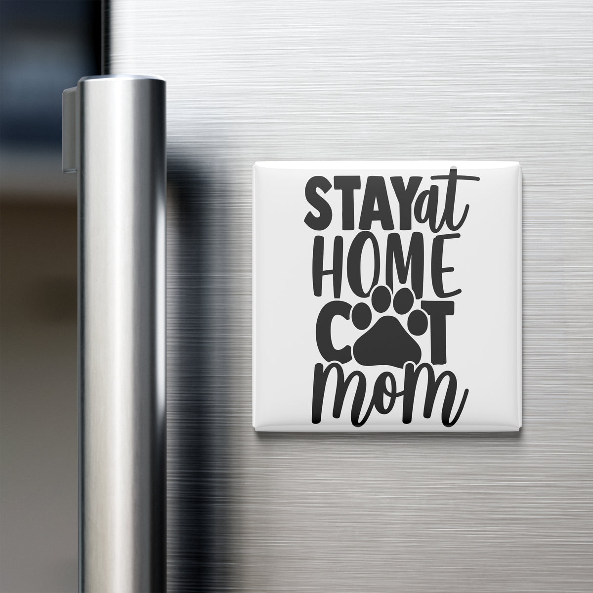 A white refrigerator magnet with the text "STAY AT HOME COT MOM" in black lettering.