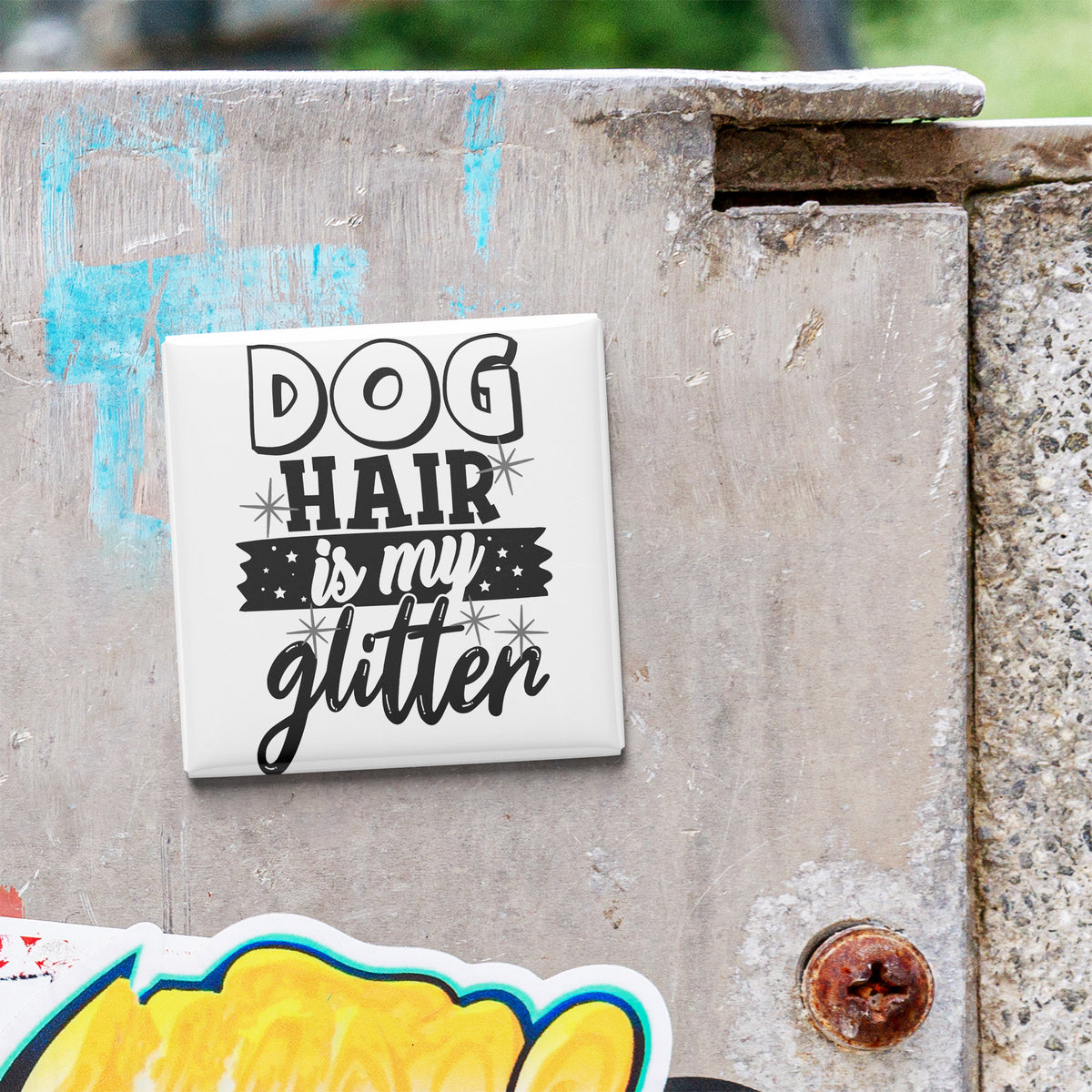 A white tile with the text "DOG HAIR IS MY GLITTER" is attached to a concrete wall.
