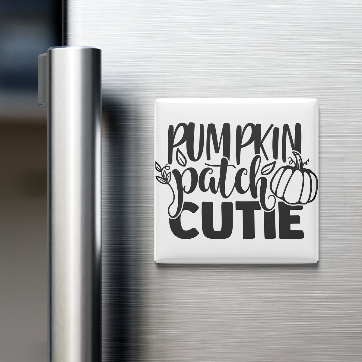 A refrigerator door with a white magnet that says "Pumpkin Patch Cutie" in black text.
