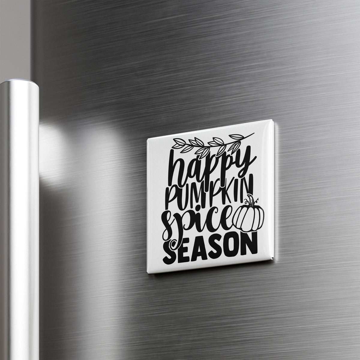 A white square magnet with black text that says "happy pumpkin spice season" is attached to a metallic surface.