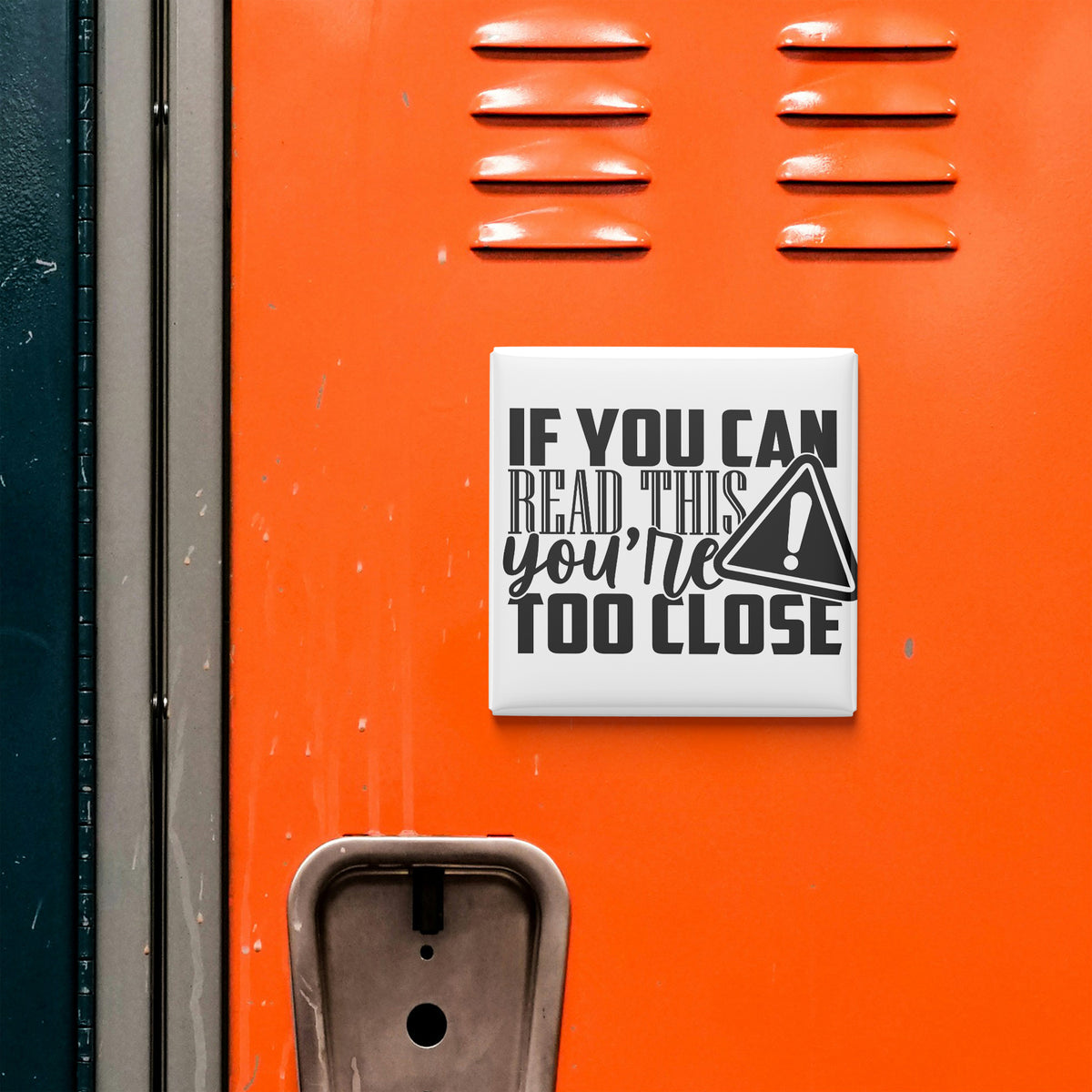a sign with the text "IF YOU CAN READ THIS YOU'RE TOO CLOSE" on an orange surface, which appears to be a locker or a storage unit.
