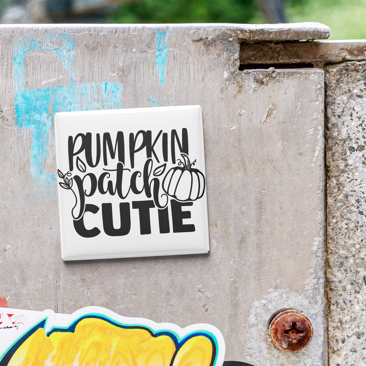 a white square tile with the text "Rumpkin Patch Cutie" written on it, which is attached to a concrete wall.