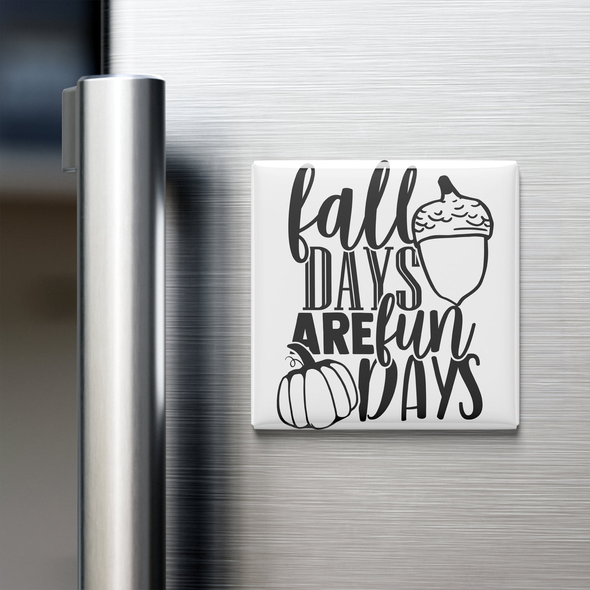 A refrigerator door with a magnet that says "fall days are fun days" along with an illustration of a pumpkin and an acorn.