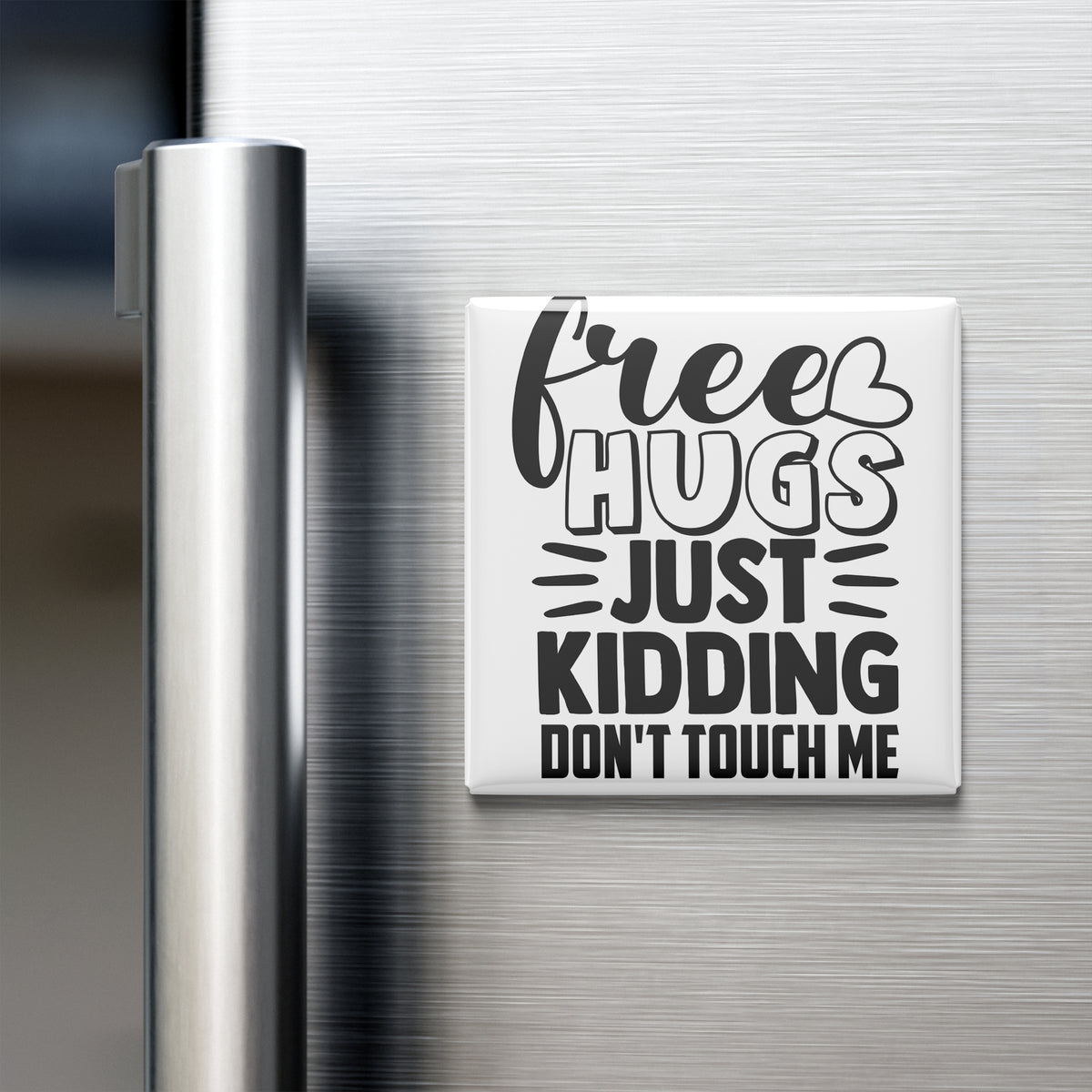 A white refrigerator magnet with black text that reads "Free Hugs Just Kidding Don't Touch Me".
