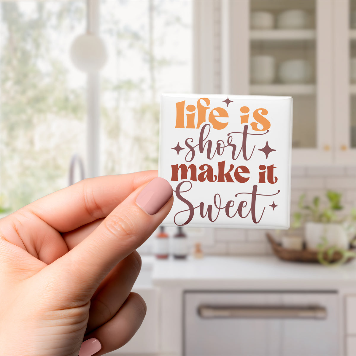 A hand holding a small white object with text on it, which appears to be a magnet or sticker.