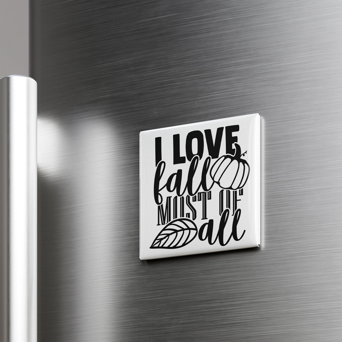 A white square magnet with the text "I LOVE fall MOST of all" printed on it, attached to a metallic surface.