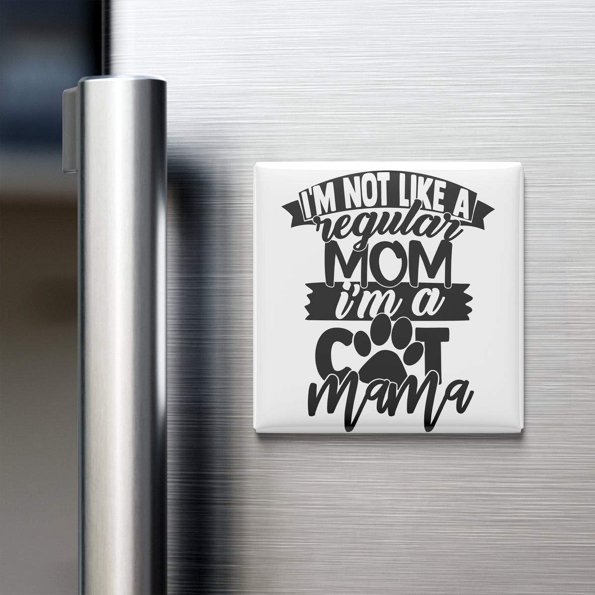 A refrigerator door with a humorous magnet that reads "I'm not like a regular mom, I'm a cool mama" in a playful, tongue-in-cheek font.