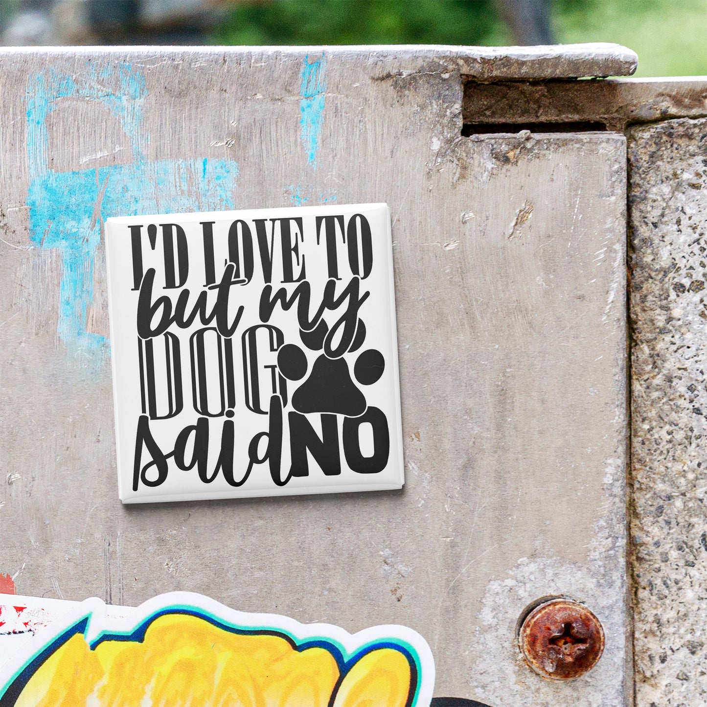 a sticker with the text "I'D LOVE TO BUT MY DOG SAID NO" on a concrete surface.