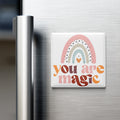 A colorful magnet with a rainbow design and the text "You are magic" on a refrigerator.