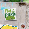A sticker with a cartoon pickle and the text "I'm a pickle" is attached to a concrete surface.