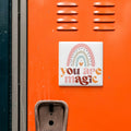 a vibrant orange wall with a white sticker that reads "You are magic" in a playful, colorful font.