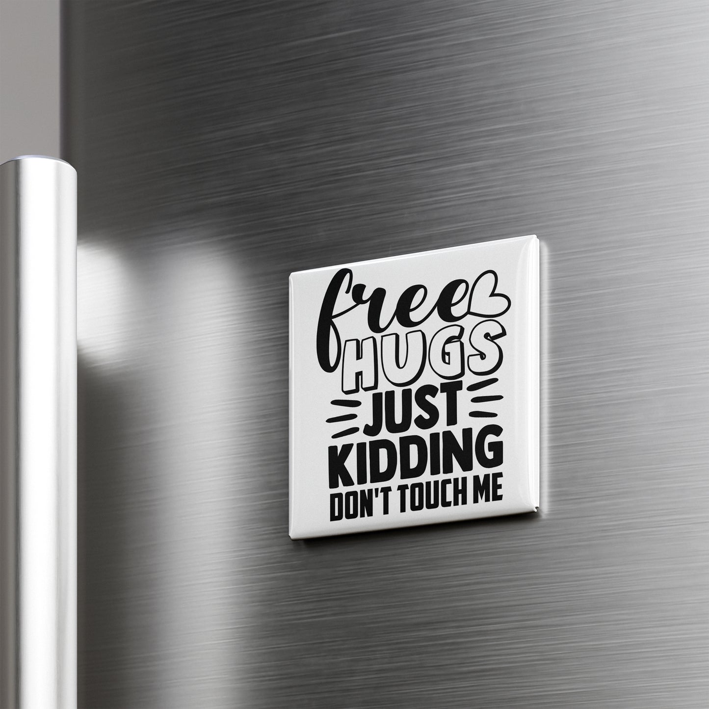 A white refrigerator door with a black and white magnet that says "Free Hugs Just Kidding Don't Touch Me".