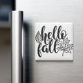 A refrigerator door with a magnet that says "Hello fall" along with a leaf graphic.