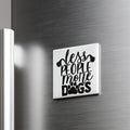A white magnet with the text "less people, more dogs" printed on it is attached to a metallic surface.
