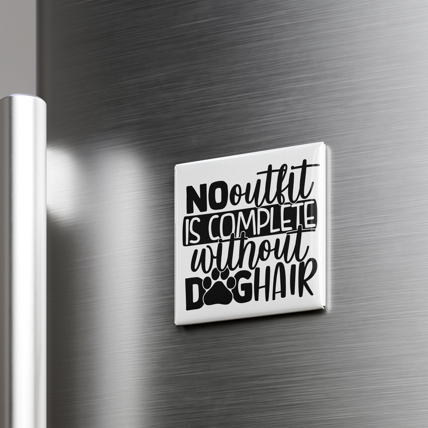 a white square magnet with the text "NO outfit is complete without dog hair" printed on it.