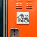 a close-up of an orange surface with a white sign that reads "home is where the cat is".