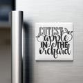 a refrigerator with a white magnet that says "CUTEST APPLE IN THE ORCHARD" in a decorative font.