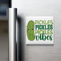 A refrigerator door with a magnet that says "Pickles, Pickles, Vibes" featuring a cartoon pickle.