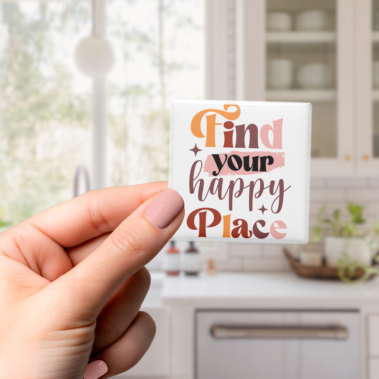 A hand holding a small white magnet with the text "Find your happy place" written on it.
