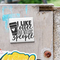 a sticker with the text "I LIKE coffee AND MAYBE 3 PEOPLE" on a concrete surface.