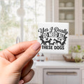 A person's hand holding a small square magnet with a humorous text and graphic design.