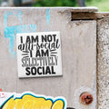 a sticker with the text "I am not anti-social I am selectively social" on a concrete surface.