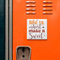 a vibrant orange wall with a white square sticker that reads "Life is short make it sweet".