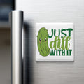 A refrigerator magnet with a cartoon pickle and the text "Just dill with it" on it.